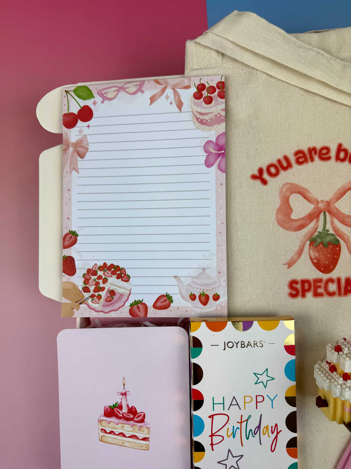 Strawberry and dessert-themed lined notepad with illustrated birthday cake greeting card and Joybars Happy Birthday milk chocolate in a birthday gift box
