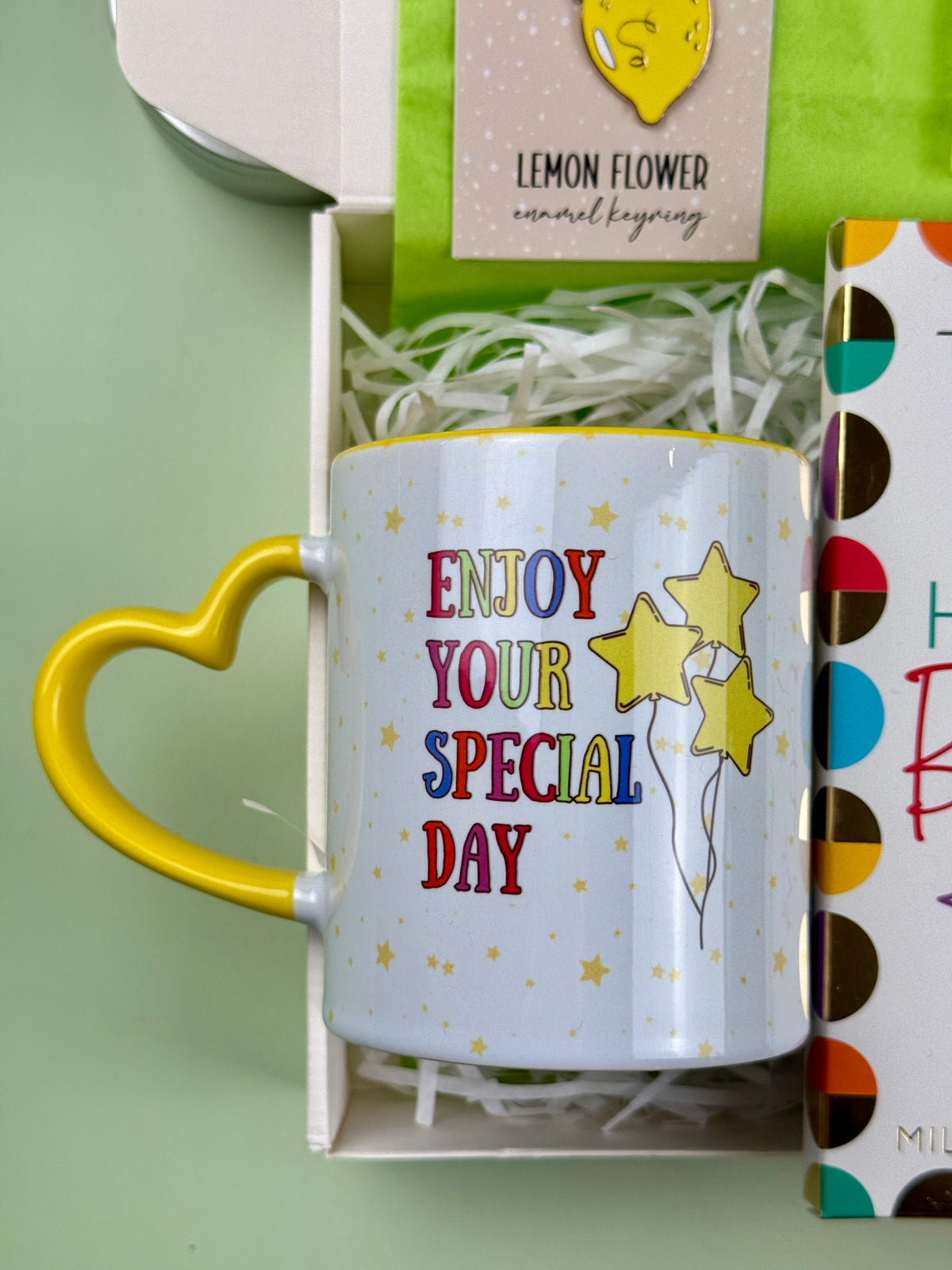 White birthday mug with yellow heart-shaped handle, colorful lettering and Enjoy Your Special Day message