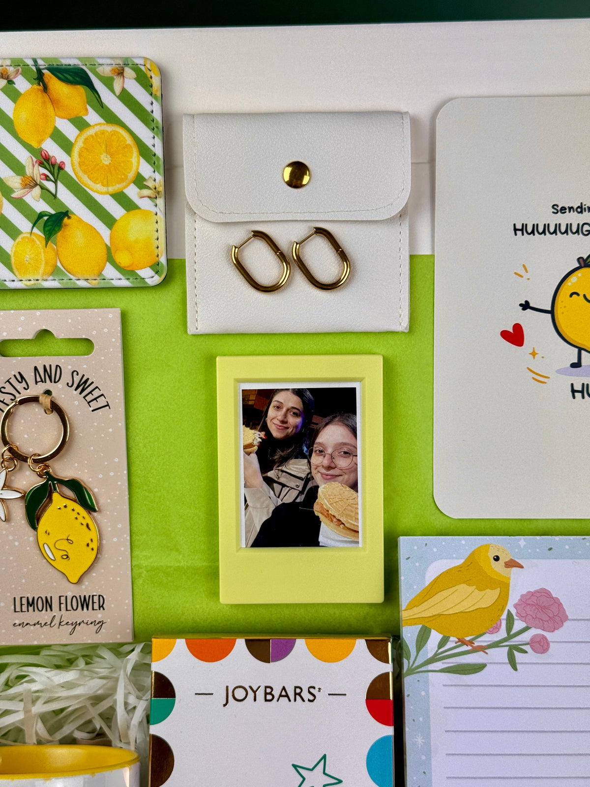 Gold-tone hoop earrings in a white pouch and a yellow mini photo frame included in a personalized birthday gift set