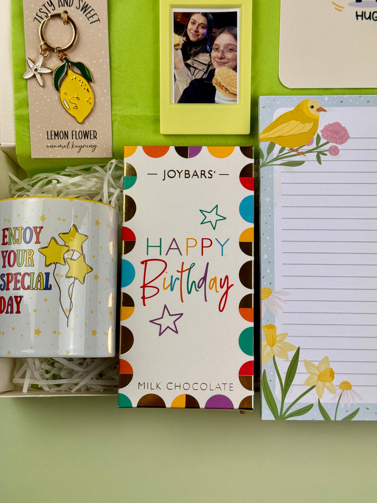 Joybars Happy Birthday milk chocolate bar with colorful packaging, displayed beside a birthday mug and floral notepad
